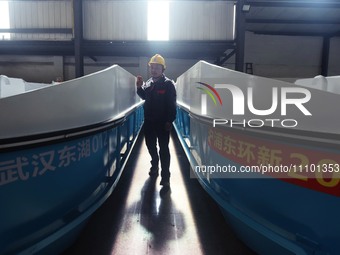 A worker is inspecting the self-developed water surface cleaning long arm environmental protection ship at a shipping company's factory buil...