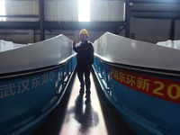 A worker is inspecting the self-developed water surface cleaning long arm environmental protection ship at a shipping company's factory buil...