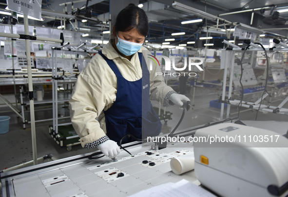 A worker is working on a production line of wiring harness products for a complete vehicle at a workshop of a technology company in Fuyang,...