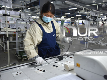 A worker is working on a production line of wiring harness products for a complete vehicle at a workshop of a technology company in Fuyang,...