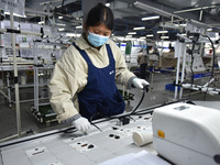 A worker is working on a production line of wiring harness products for a complete vehicle at a workshop of a technology company in Fuyang,...