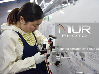 A worker is working on a production line of wiring harness products for a complete vehicle at a workshop of a technology company in Fuyang,...