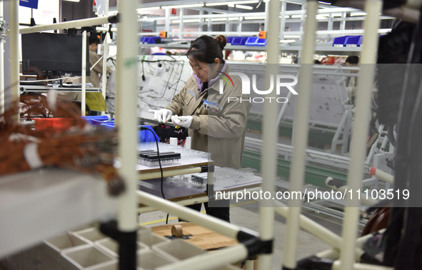 A worker is working on a production line of wiring harness products for a complete vehicle at a workshop of a technology company in Fuyang,...