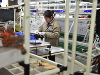 A worker is working on a production line of wiring harness products for a complete vehicle at a workshop of a technology company in Fuyang,...