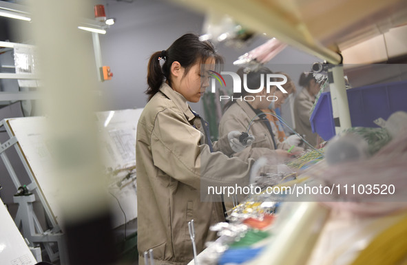 Workers are working on a production line of wiring harness products for complete vehicles at a workshop of a technology company in Fuyang, C...