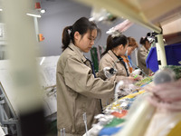 Workers are working on a production line of wiring harness products for complete vehicles at a workshop of a technology company in Fuyang, C...