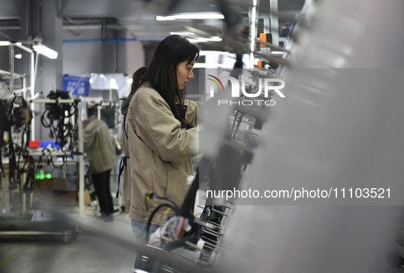 A worker is working on a production line of wiring harness products for a complete vehicle at a workshop of a technology company in Fuyang,...