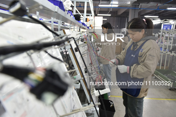 Workers are working on a production line of wiring harness products for complete vehicles at a workshop of a technology company in Fuyang, C...