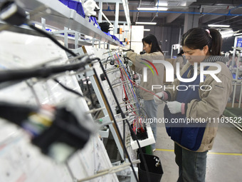 Workers are working on a production line of wiring harness products for complete vehicles at a workshop of a technology company in Fuyang, C...