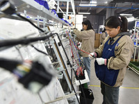 Workers are working on a production line of wiring harness products for complete vehicles at a workshop of a technology company in Fuyang, C...