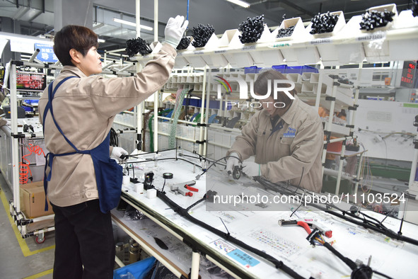 Workers are working on a production line of wiring harness products for complete vehicles at a workshop of a technology company in Fuyang, C...