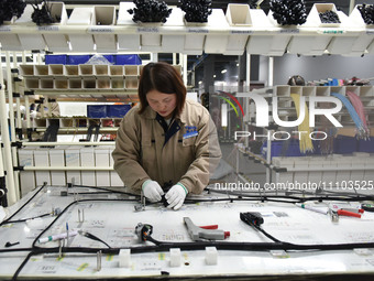 A worker is working on a production line of wiring harness products for a complete vehicle at a workshop of a technology company in Fuyang,...