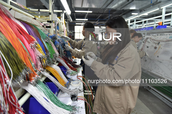 Workers are working on a production line of wiring harness products for complete vehicles at a workshop of a technology company in Fuyang, C...