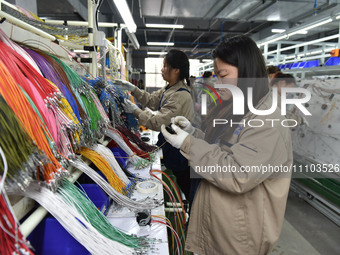 Workers are working on a production line of wiring harness products for complete vehicles at a workshop of a technology company in Fuyang, C...