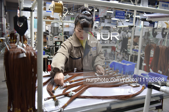 A worker is working on a production line of wiring harness products for a complete vehicle at a workshop of a technology company in Fuyang,...