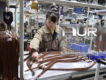 A worker is working on a production line of wiring harness products for a complete vehicle at a workshop of a technology company in Fuyang,...