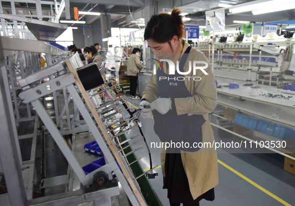 Workers are working on a production line of wiring harness products for complete vehicles at a workshop of a technology company in Fuyang, C...