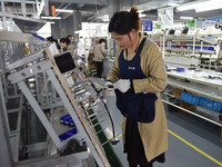 Workers are working on a production line of wiring harness products for complete vehicles at a workshop of a technology company in Fuyang, C...