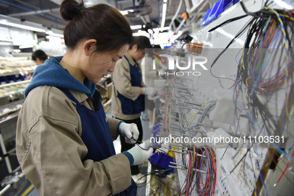 Workers are working on a production line of wiring harness products for complete vehicles at a workshop of a technology company in Fuyang, C...