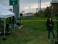 The collapsed Francis Scott Key Bridge is seen beyond a reporter at a media staging area at the Maryland Tansportation Authority headquarter...