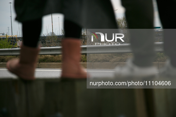 The collapsed Francis Scott Key Bridge is seen beyond the feet of people viewing the bridge from the Broening Highway in Dundalk, Maryland o...