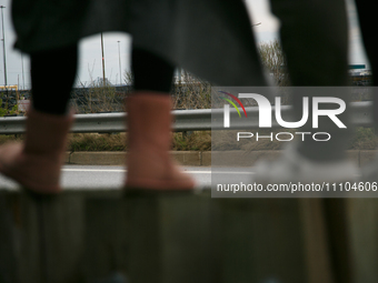 The collapsed Francis Scott Key Bridge is seen beyond the feet of people viewing the bridge from the Broening Highway in Dundalk, Maryland o...