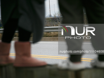 The collapsed Francis Scott Key Bridge is seen beyond the feet of people viewing the bridge from the Broening Highway in Dundalk, Maryland o...