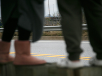 The collapsed Francis Scott Key Bridge is seen beyond the feet of people viewing the bridge from the Broening Highway in Dundalk, Maryland o...