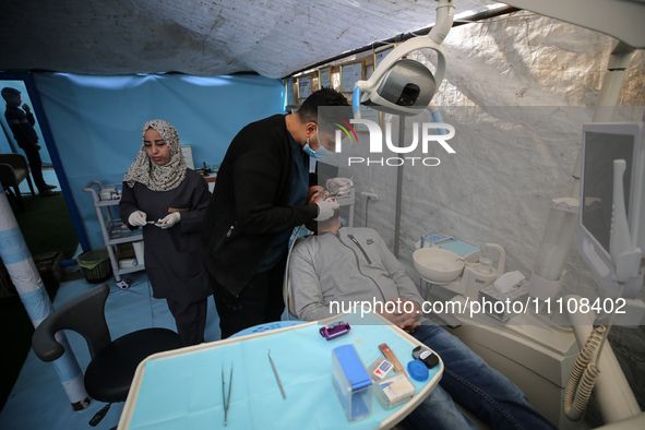 Palestinian dentist Najdat Saqr is treating his patients in a tent in the refugee camp in the central Gaza Strip on March 30, 2024, after hi...