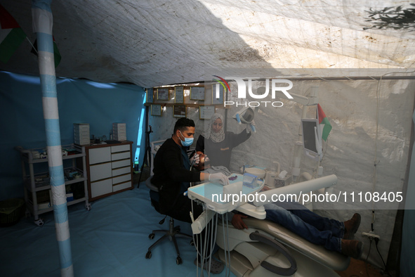 Palestinian dentist Najdat Saqr is treating his patients in a tent in the refugee camp in the central Gaza Strip on March 30, 2024, after hi...