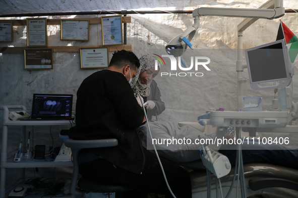 Palestinian dentist Najdat Saqr is treating his patients in a tent in the refugee camp in the central Gaza Strip on March 30, 2024, after hi...