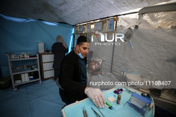 Palestinian dentist Najdat Saqr is treating his patients in a tent in the refugee camp in the central Gaza Strip on March 30, 2024, after hi...