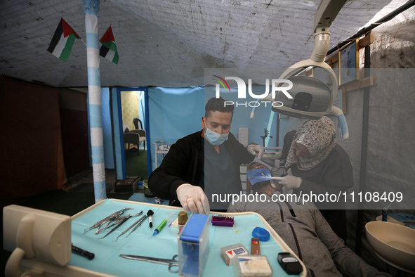 Palestinian dentist Najdat Saqr is treating his patients in a tent in the refugee camp in the central Gaza Strip on March 30, 2024, after hi...