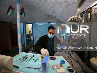Palestinian dentist Najdat Saqr is treating his patients in a tent in the refugee camp in the central Gaza Strip on March 30, 2024, after hi...