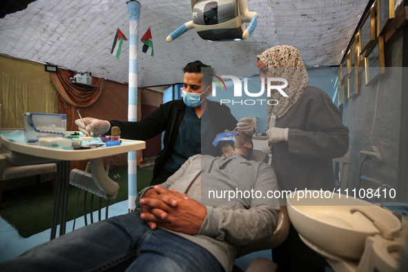 Palestinian dentist Najdat Saqr is treating his patients in a tent in the refugee camp in the central Gaza Strip on March 30, 2024, after hi...