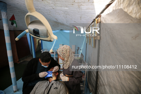 Palestinian dentist Najdat Saqr is treating his patients in a tent in the refugee camp in the central Gaza Strip on March 30, 2024, after hi...