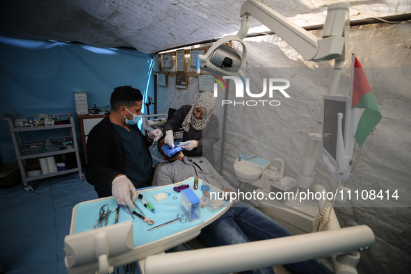 Palestinian dentist Najdat Saqr is treating his patients in a tent in the refugee camp in the central Gaza Strip on March 30, 2024, after hi...