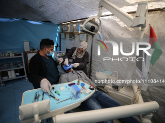 Palestinian dentist Najdat Saqr is treating his patients in a tent in the refugee camp in the central Gaza Strip on March 30, 2024, after hi...