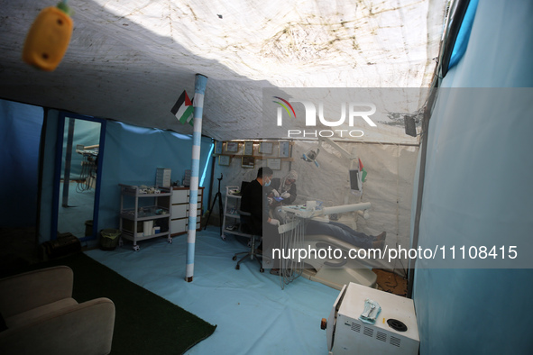 Palestinian dentist Najdat Saqr is treating his patients in a tent in the refugee camp in the central Gaza Strip on March 30, 2024, after hi...