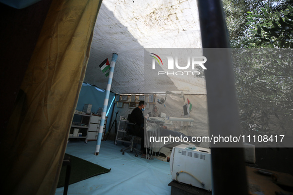 Palestinian dentist Najdat Saqr is treating his patients in a tent in the refugee camp in the central Gaza Strip on March 30, 2024, after hi...