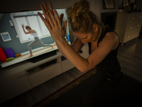 A woman is seen doing yoga exercises with YouTube trainer on a television in her living room in Warsaw, Poland on 23 March, 2024. (