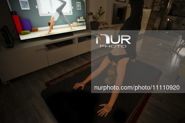 A woman is seen doing yoga exercises with YouTube trainer on a television in her living room in Warsaw, Poland on 23 March, 2024. 