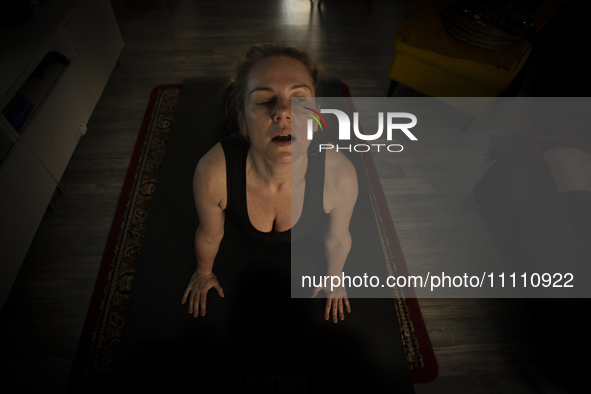 A woman is seen doing yoga exercises with YouTube trainer on a television in her living room in Warsaw, Poland on 23 March, 2024. 