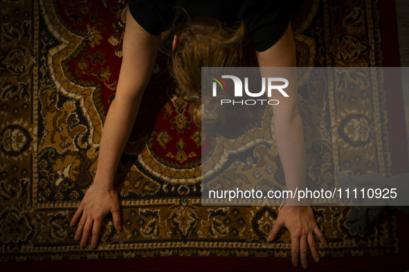 A woman is seen doing yoga exercises with YouTube trainer on a television in her living room in Warsaw, Poland on 23 March, 2024. 