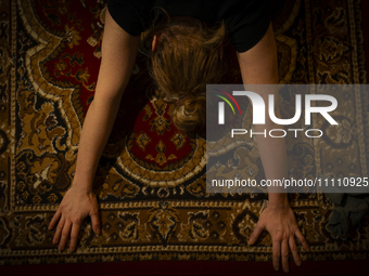 A woman is seen doing yoga exercises with YouTube trainer on a television in her living room in Warsaw, Poland on 23 March, 2024. (