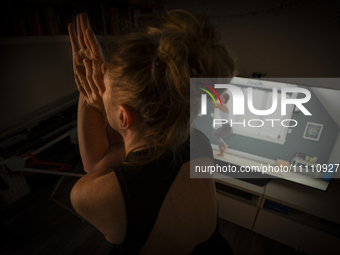 A woman is seen doing yoga exercises with YouTube trainer on a television in her living room in Warsaw, Poland on 23 March, 2024. (