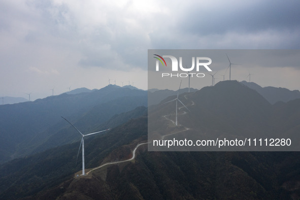 Wind turbines are standing above the rolling green mountains at the Xiutang Township wind farm in Congjiang County, Guizhou Province, China,...