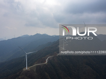 Wind turbines are standing above the rolling green mountains at the Xiutang Township wind farm in Congjiang County, Guizhou Province, China,...