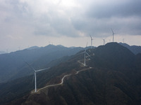 Wind turbines are standing above the rolling green mountains at the Xiutang Township wind farm in Congjiang County, Guizhou Province, China,...