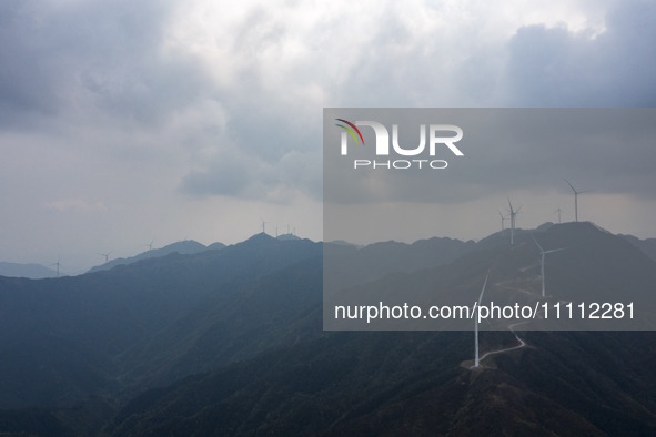 Wind turbines are standing above the rolling green mountains at the Xiutang Township wind farm in Congjiang County, Guizhou Province, China,...